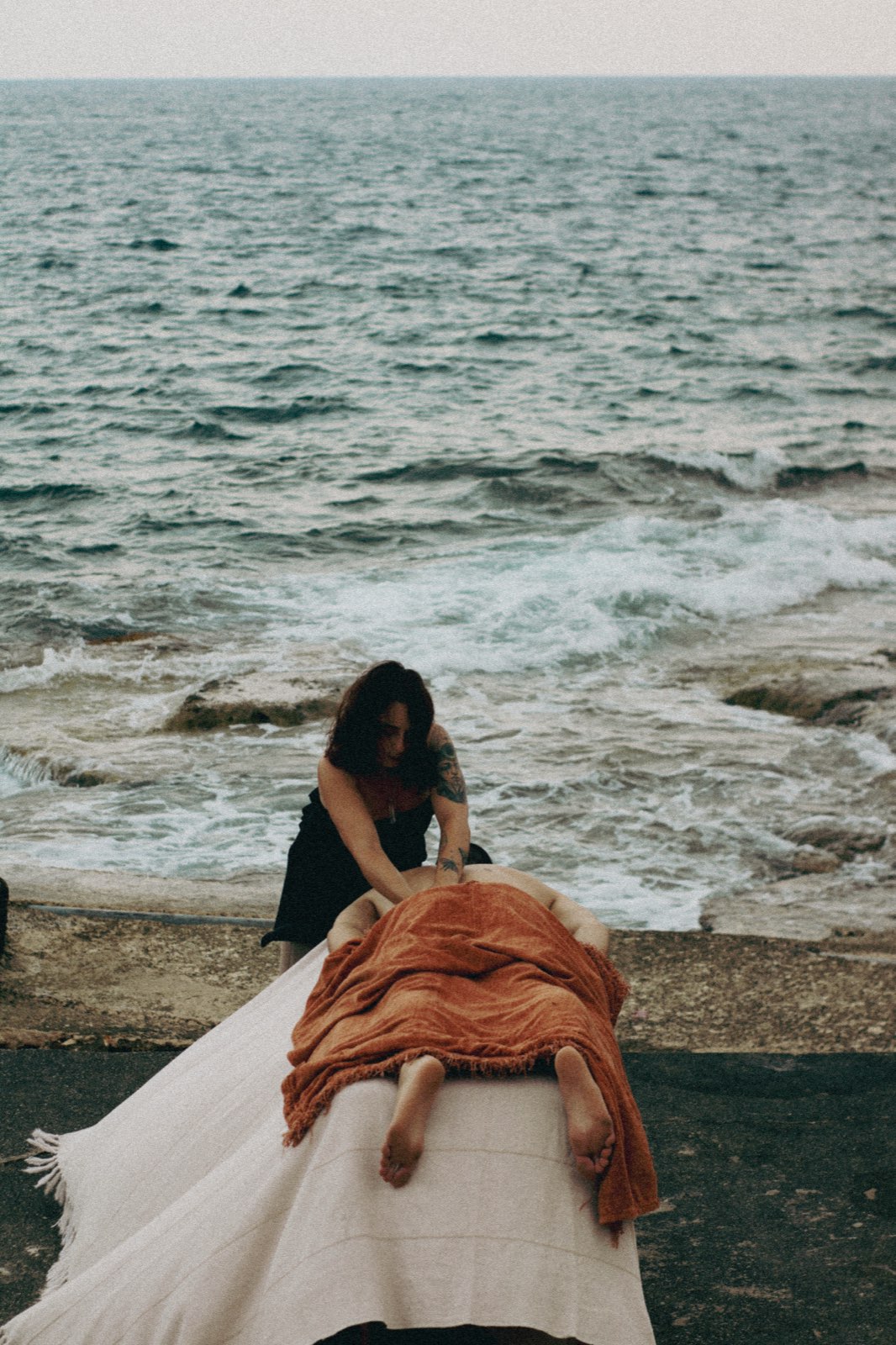 Jules giving a massage on a table set by the Mediterranean sea
